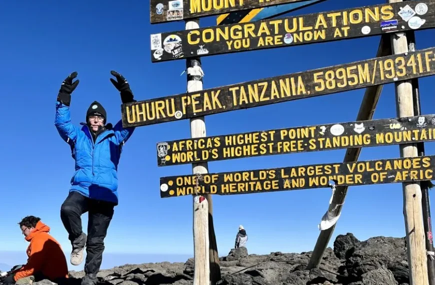 Climbers celebrating at Kilimanjaro summit sign